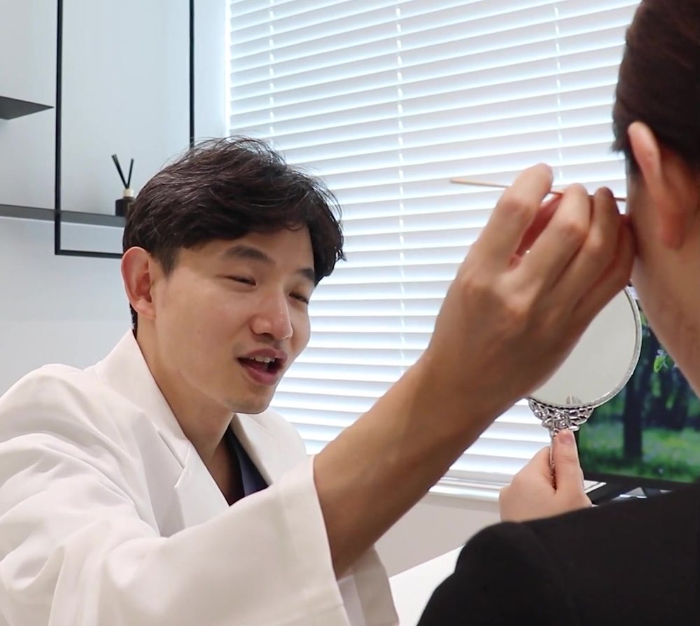 흰 가운 의사가 손거울을 든 환자에게 설명하는 상담 장면