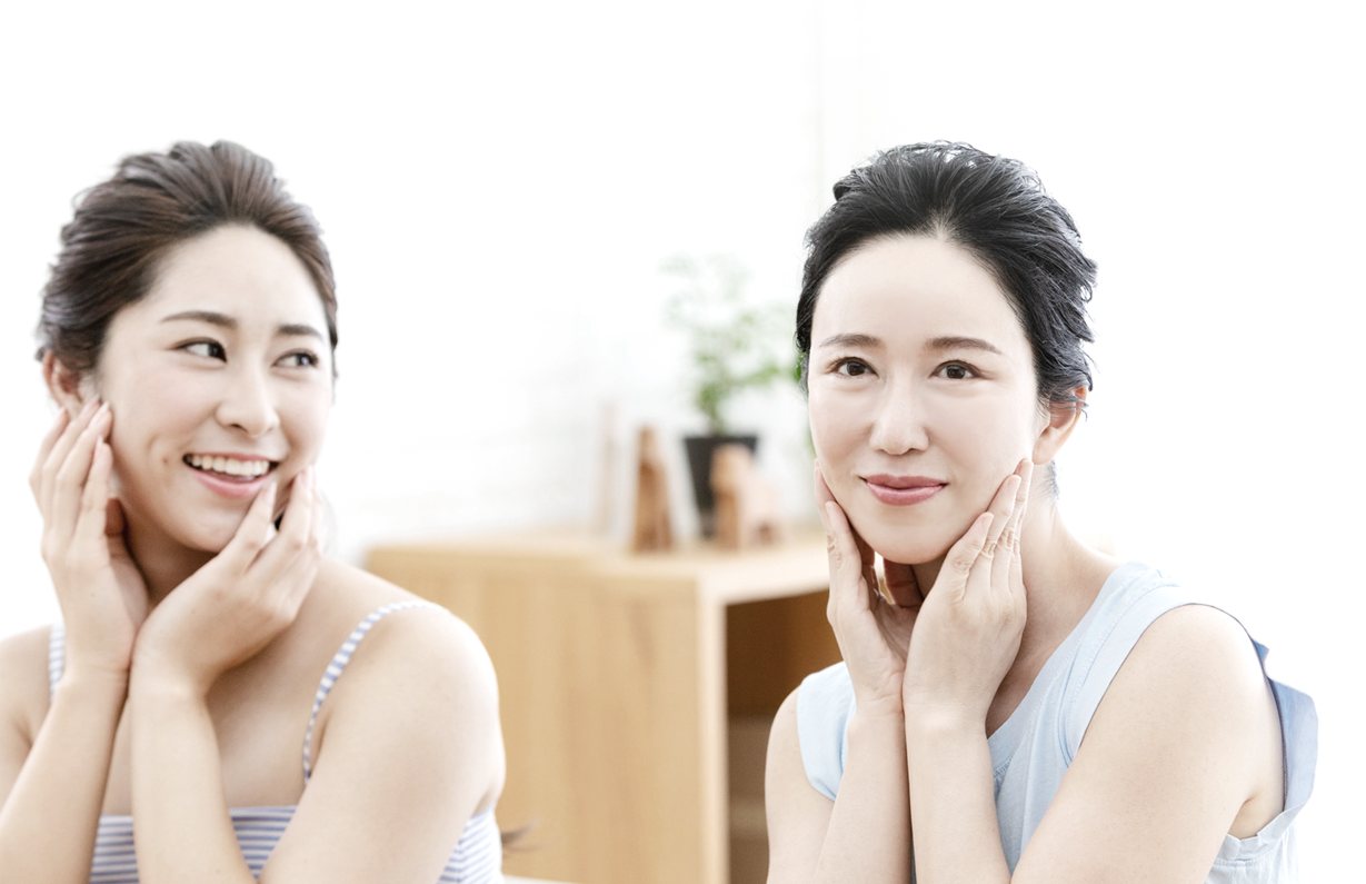 거울 앞에서 손으로 볼을 감싼 젊은 여성과 중년 여성 모델(엄마와 딸 연출)